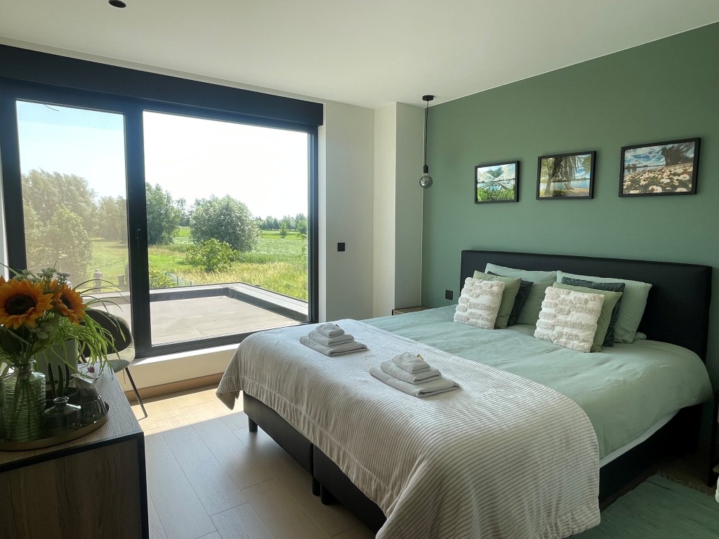 Groene master slaapkamer met groot tweepersoonsbed en badjassen